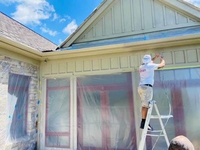 Man on a ladder painting the exterior of a home